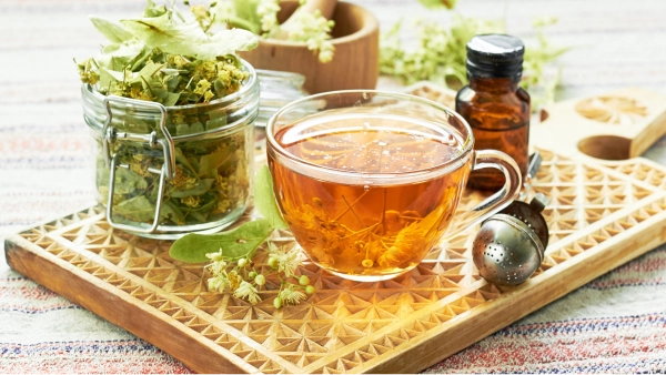Une tasse de thé et un bocal de feuilles sur un plateau de table.