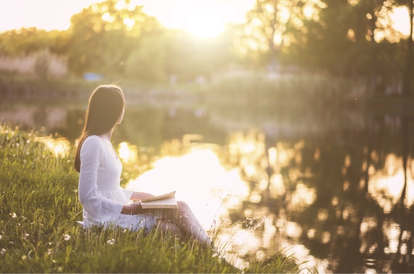 Femme assise au bord d'un lac.